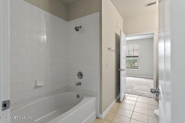 bathroom featuring tile patterned flooring, tiled shower / bath combo, toilet, and a textured ceiling