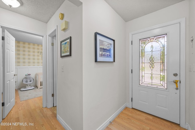 entryway with light hardwood / wood-style floors and a textured ceiling