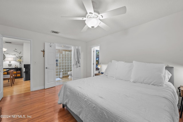 bedroom with hardwood / wood-style floors, ensuite bath, and ceiling fan