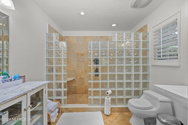 bathroom with tile patterned flooring, a textured ceiling, tiled shower, and toilet