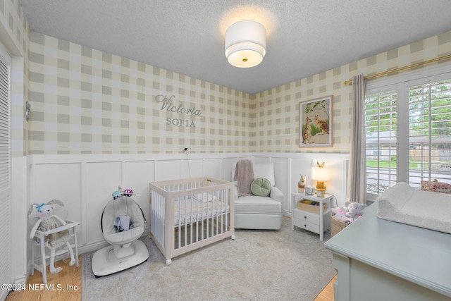 bedroom featuring a textured ceiling and a nursery area