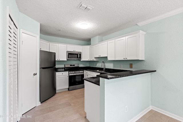 1701 The Greens Way Unit 311, Jacksonville Beach, FL 32250 - kitchen featuring appliances with stainless steel finishes, a peninsula, white cabinets, a textured ceiling, and light tile patterned floors