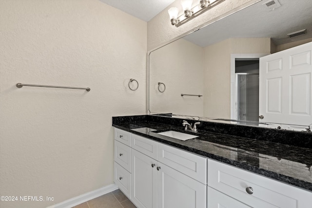 bathroom with tile patterned flooring, a textured ceiling, vanity, and an enclosed shower