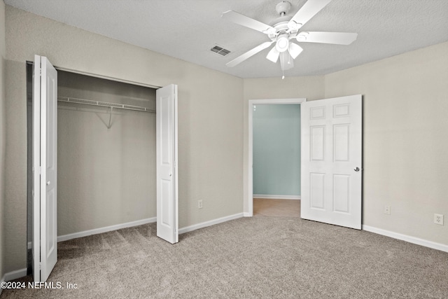 unfurnished bedroom with carpet flooring, a textured ceiling, a closet, and ceiling fan