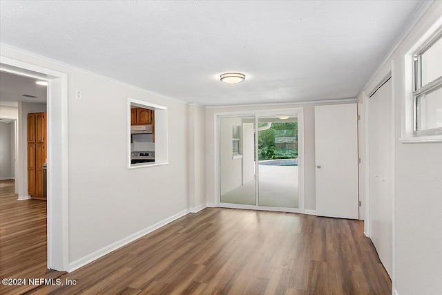 interior space featuring crown molding, dark wood-type flooring, and a textured ceiling