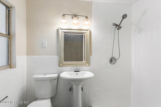 bathroom with tiled shower, tile walls, and toilet