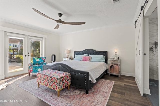 bedroom with a barn door, ceiling fan, dark wood-type flooring, and ornamental molding