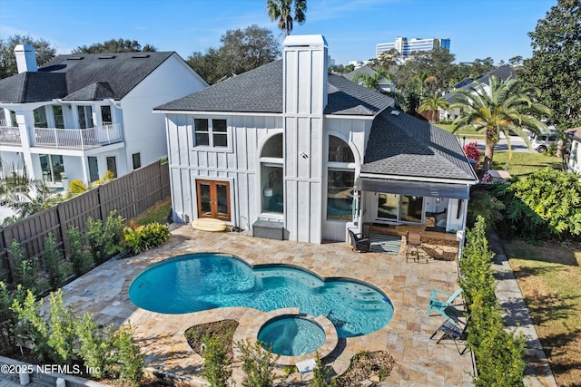 back of property featuring french doors, a patio, and a pool with hot tub