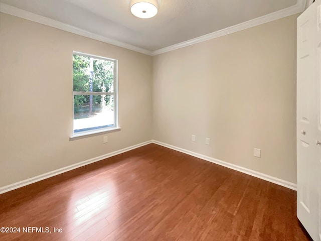 empty room featuring ornamental molding and dark wood-type flooring