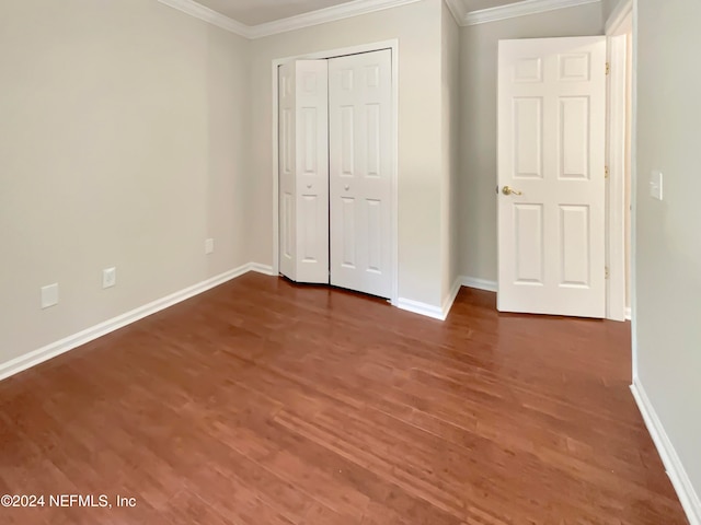 unfurnished bedroom featuring crown molding, a closet, and dark wood-type flooring