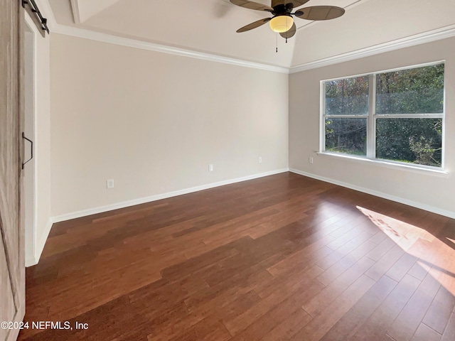 spare room featuring ceiling fan, a barn door, dark hardwood / wood-style flooring, and crown molding