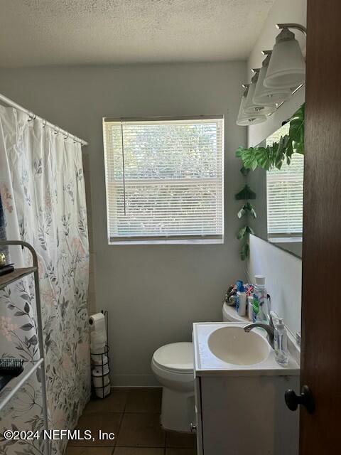 bathroom with tile patterned floors, vanity, a textured ceiling, toilet, and curtained shower