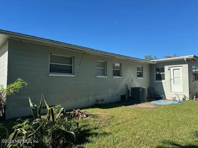 back of property with central AC unit and a lawn