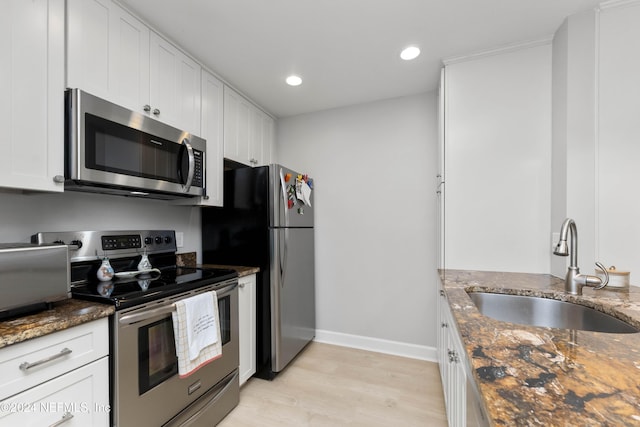 410 1st St S Unit C, Jacksonville Beach, FL 32250 - kitchen featuring appliances with stainless steel finishes, a sink, dark stone countertops, light wood-type flooring, and baseboards