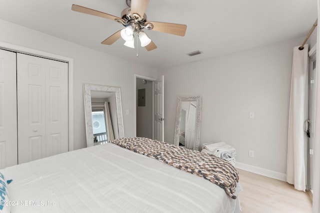 bedroom with electric panel, ceiling fan, a closet, and light hardwood / wood-style floors