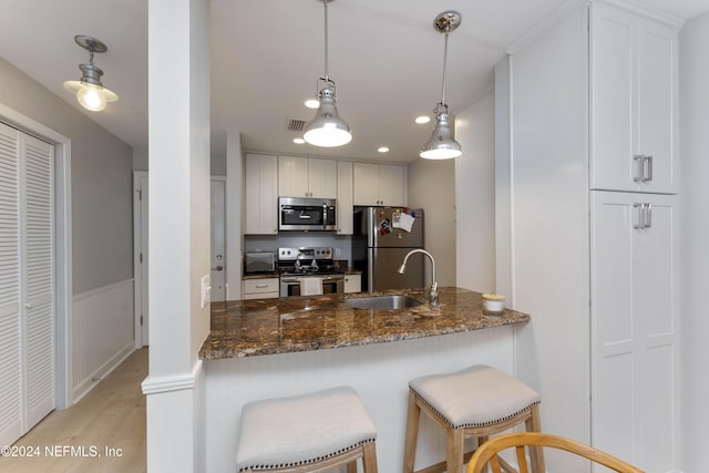410 1st St S Unit C, Jacksonville Beach, FL 32250 - kitchen with appliances with stainless steel finishes, a sink, light wood-style floors, dark stone countertops, and a wainscoted wall