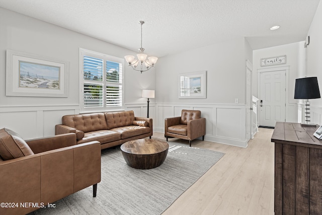 living room featuring a chandelier, light hardwood / wood-style floors, and a textured ceiling