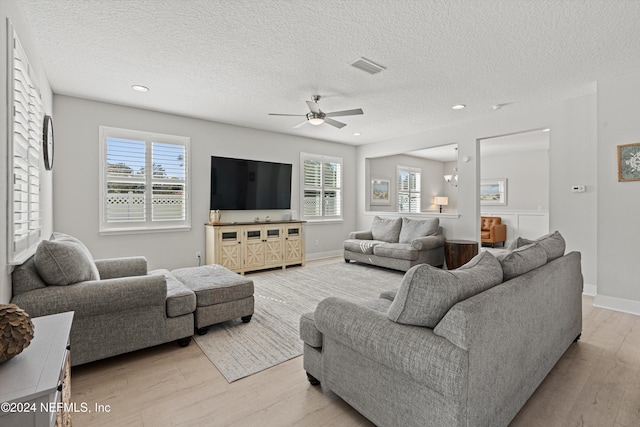 living room featuring a textured ceiling, light hardwood / wood-style flooring, and plenty of natural light