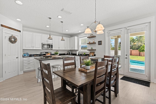 dining room with a chandelier, sink, light hardwood / wood-style floors, and a textured ceiling