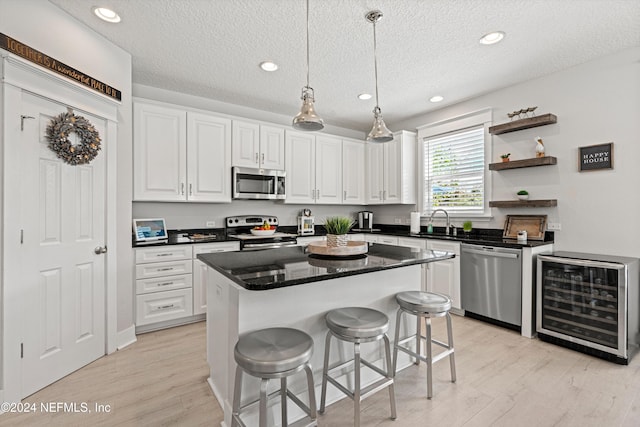 kitchen featuring wine cooler, white cabinetry, a kitchen island, and appliances with stainless steel finishes