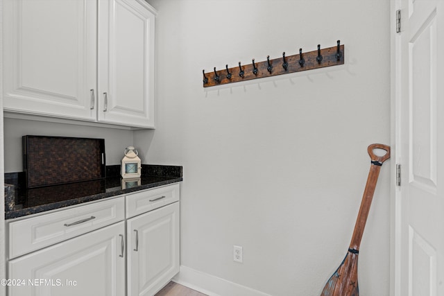 bar with dark stone countertops and white cabinetry