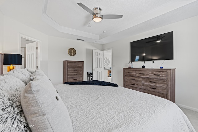 carpeted bedroom featuring ceiling fan, a raised ceiling, and a textured ceiling