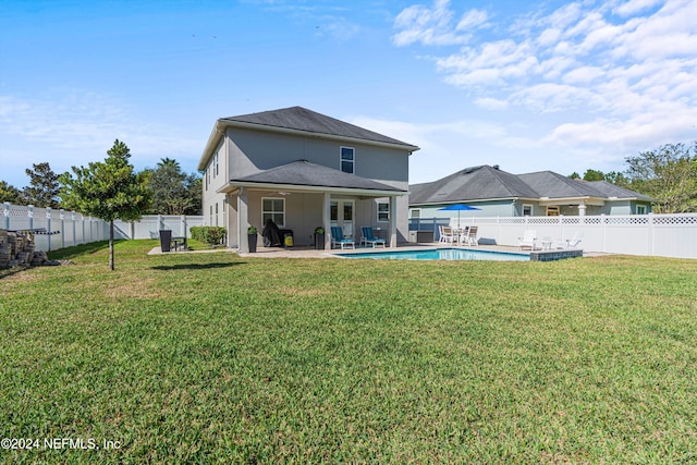 rear view of house with a fenced in pool, a yard, and a patio