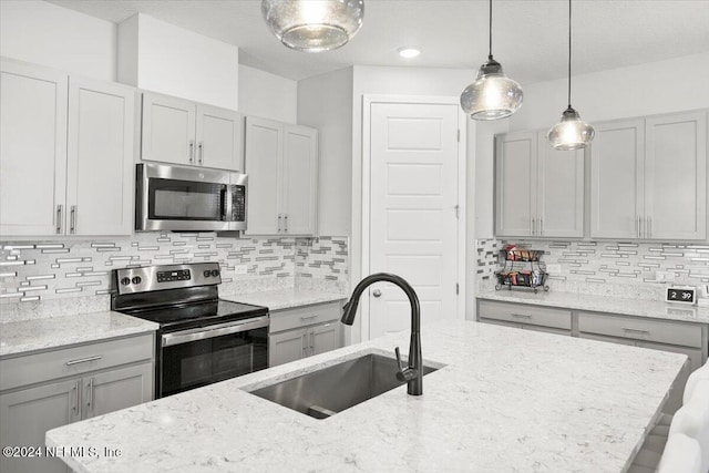 kitchen featuring decorative backsplash, sink, light stone countertops, and appliances with stainless steel finishes