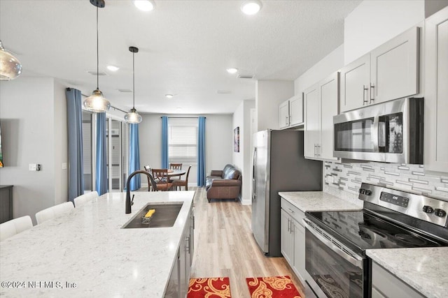 kitchen with light hardwood / wood-style floors, sink, light stone countertops, and stainless steel appliances