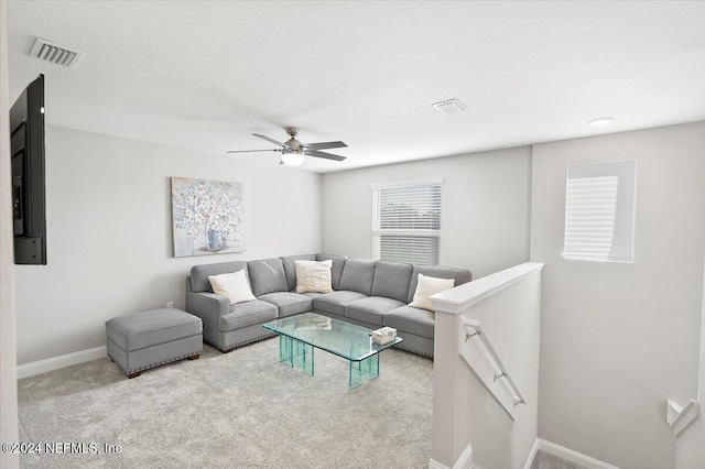 living room with a textured ceiling, light colored carpet, and ceiling fan