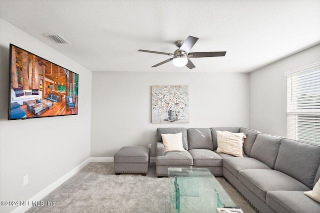 carpeted living room with ceiling fan and a textured ceiling