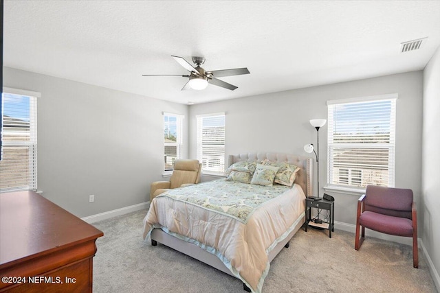 carpeted bedroom featuring multiple windows and ceiling fan