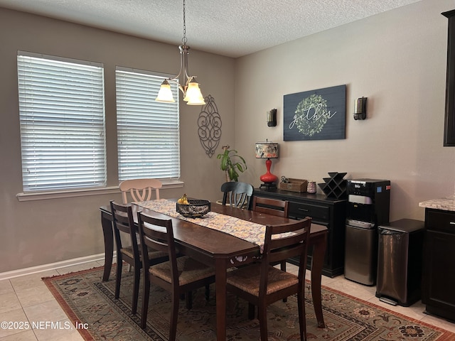 dining space with light tile patterned floors, a textured ceiling, and baseboards