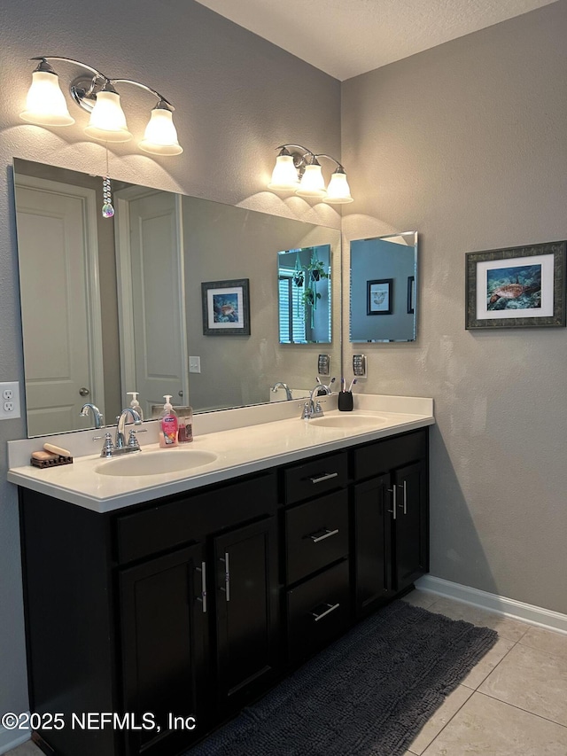 bathroom with tile patterned floors, double vanity, baseboards, and a sink
