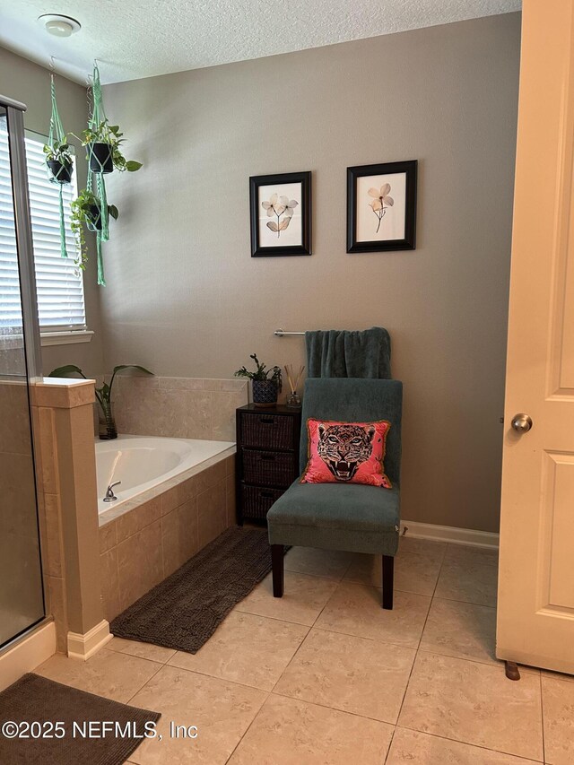 bathroom featuring tile patterned flooring, a bath, a textured ceiling, and a stall shower