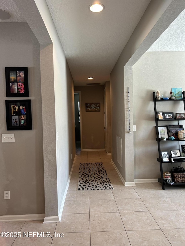 hallway featuring recessed lighting, light tile patterned floors, visible vents, and baseboards