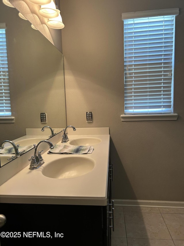 bathroom with tile patterned floors, double vanity, baseboards, and a sink