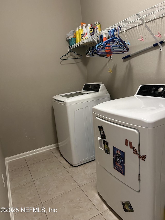 laundry area featuring light tile patterned floors, baseboards, separate washer and dryer, and laundry area