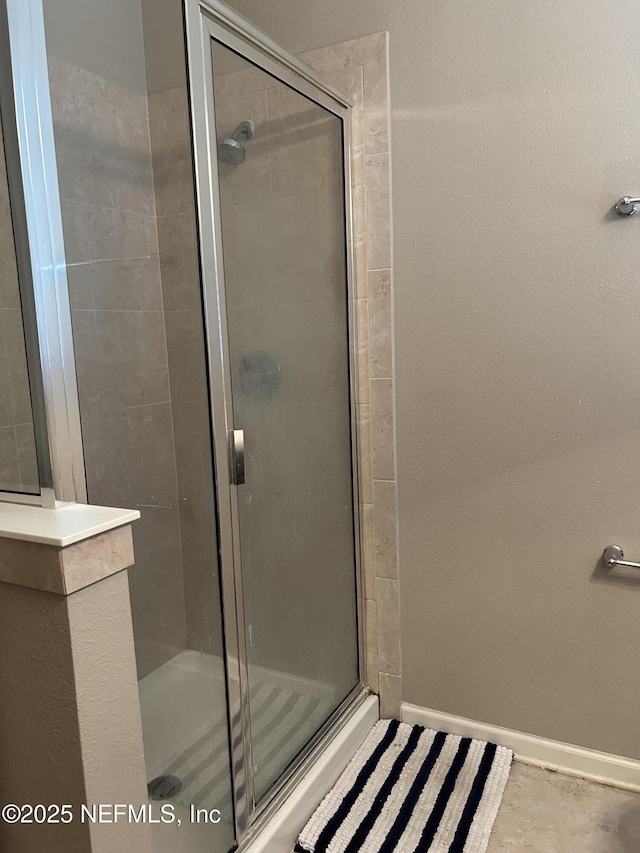 full bath with baseboards and a shower stall