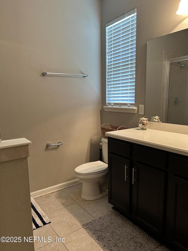bathroom with vanity, baseboards, tile patterned floors, toilet, and a shower stall