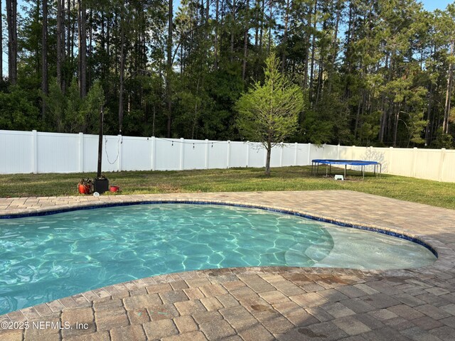 view of swimming pool featuring a trampoline, a patio area, a fenced in pool, and a fenced backyard