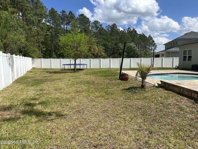view of yard featuring a fenced backyard, a trampoline, and a fenced in pool