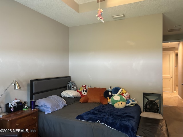 bedroom with a textured ceiling, tile patterned flooring, and visible vents