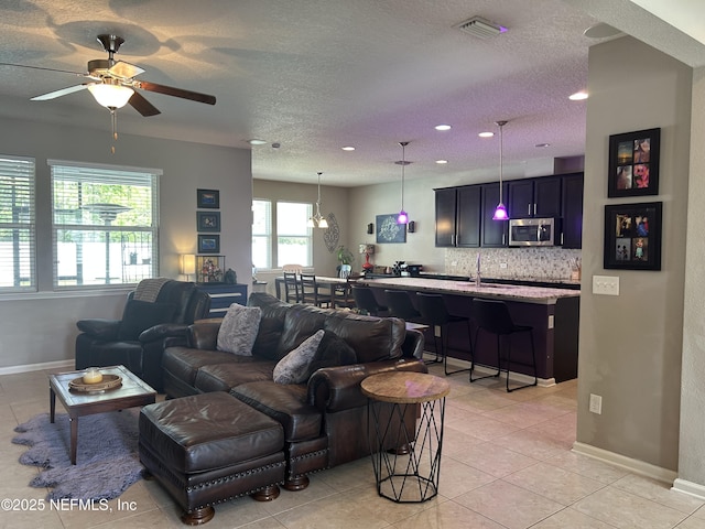living area featuring ceiling fan, light tile patterned floors, a textured ceiling, recessed lighting, and baseboards