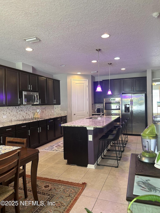 kitchen with a sink, light tile patterned floors, tasteful backsplash, and stainless steel appliances