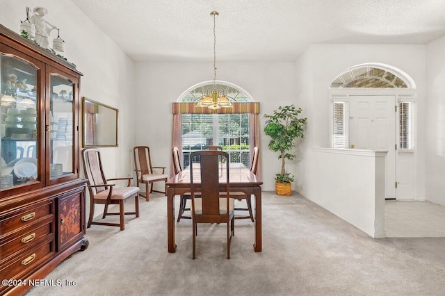 carpeted dining room featuring a chandelier and a textured ceiling