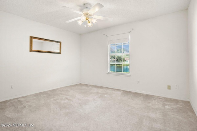 spare room with ceiling fan, light colored carpet, and a textured ceiling