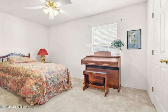 carpeted bedroom with ceiling fan and a textured ceiling