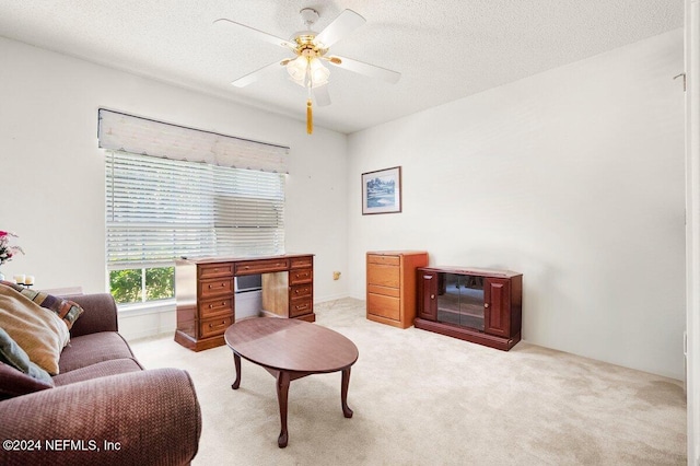 living room featuring ceiling fan, light colored carpet, and a textured ceiling