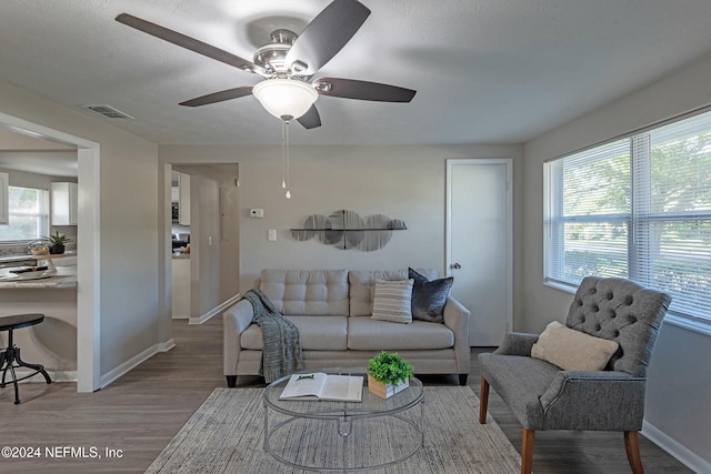 living room featuring ceiling fan, a healthy amount of sunlight, a textured ceiling, and wood-type flooring